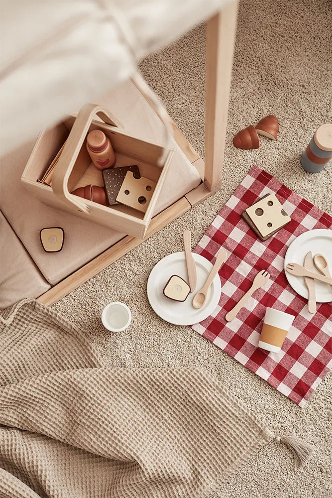 Child playing with a wooden picnic set